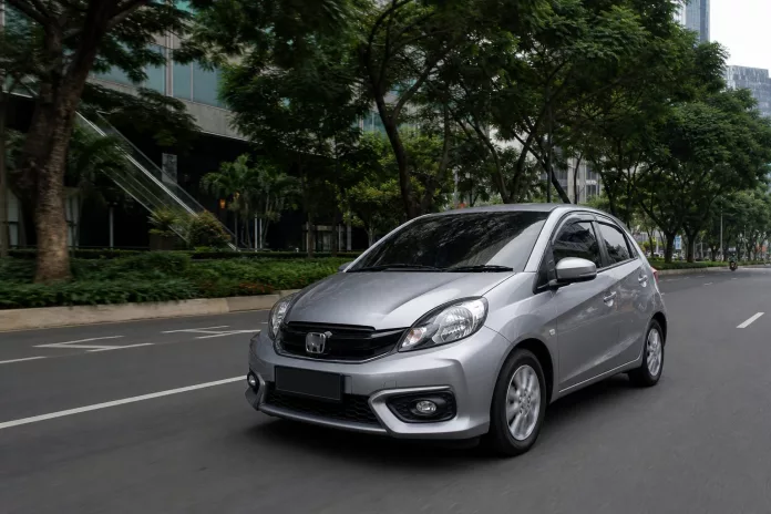 Perbandingan city car dan hatchback di jalan perkotaan yang padat, menunjukkan ukuran dan kepraktisan kedua mobil