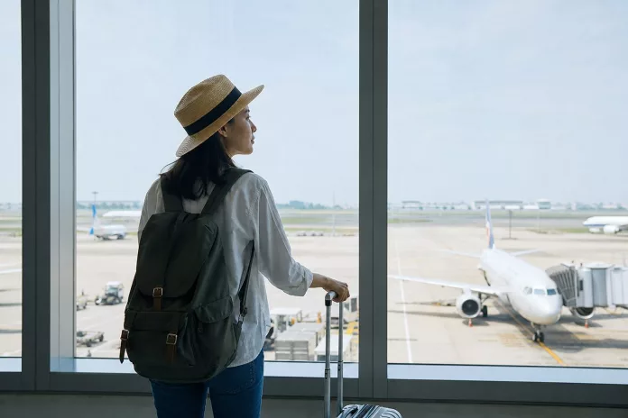 Tips Liburan Pertama ke Luar Negeri untuk Pemula Pasangan muda dengan koper berwarna-warni di bandara internasional siap untuk liburan ke luar negeri pertama mereka