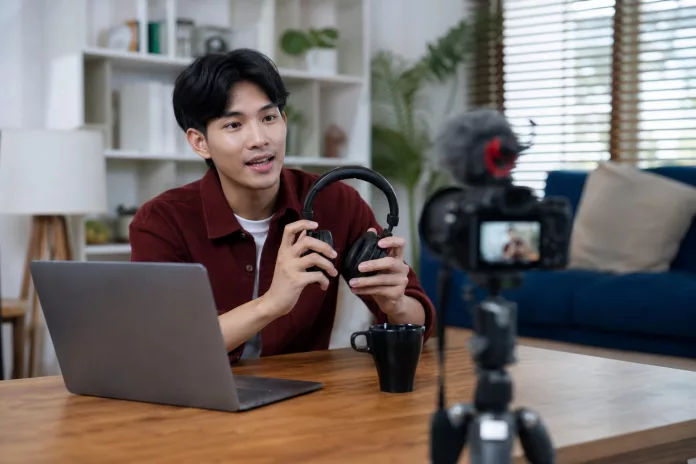 Content creator sedang membuat konten digital di depan kamera dan laptop, berbeda dengan influencer