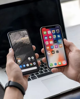 Sejarah Android vs iOS: Bagaimana Persaingannya Dimulai? Ilustrasi sejarah Android vs iOS menampilkan logo kedua sistem operasi dalam persaingan smartphone