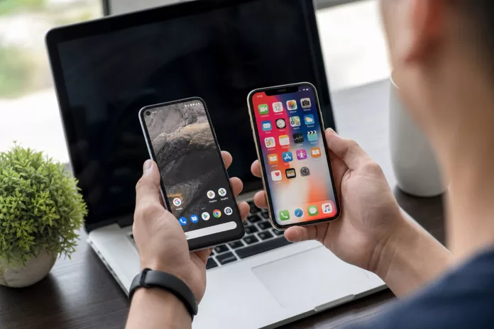 Sejarah Android vs iOS: Bagaimana Persaingannya Dimulai? Ilustrasi sejarah Android vs iOS menampilkan logo kedua sistem operasi dalam persaingan smartphone
